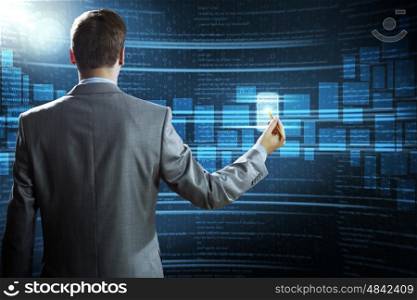 Computer technologies. Rear view of businessman touching icon of media screen