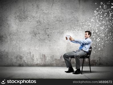 Computer technologies. Young handsome businessman looking with astonishment in tablet pc