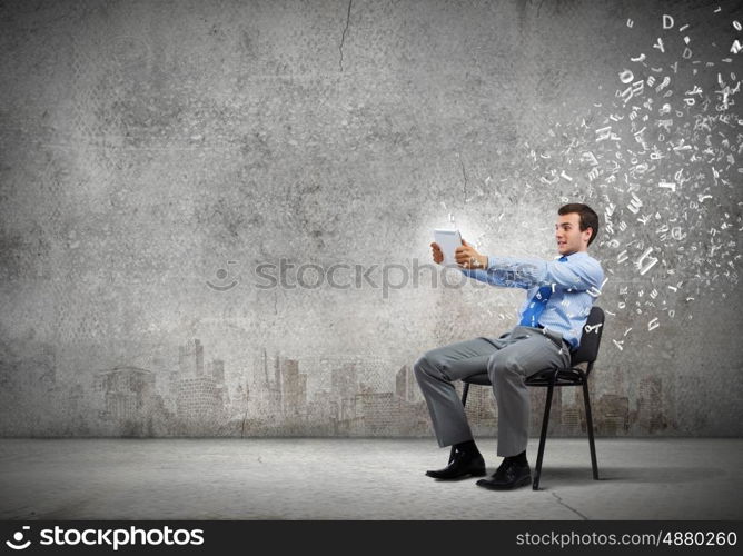 Computer technologies. Young handsome businessman looking with astonishment in tablet pc