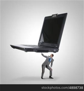 Computer work. Two young businessman lifting huge laptop above head