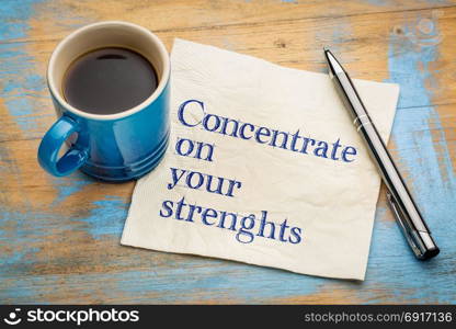 Concentrate on your strenghts - handwriting on a napkin with a cup of espresso coffee