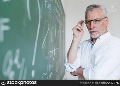 concentrated aged math teacher looking chalkboard