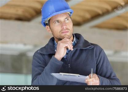concentrated builder holding a clipboard