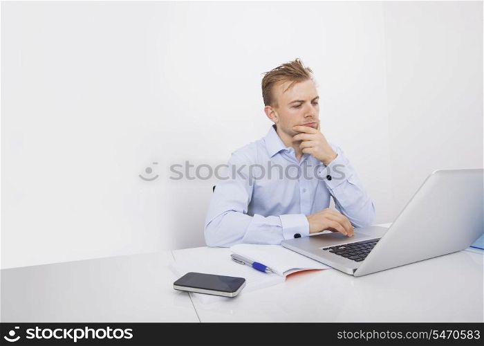 Concentrated businessman using laptop at desk in office