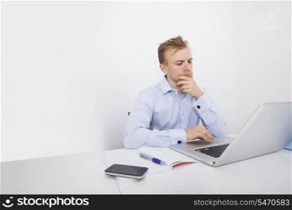 Concentrated businessman using laptop at desk in office