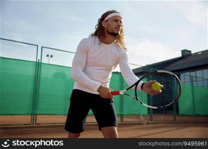 Concentrated male tennis player with racket and ball training on outdoor court. Preparation for serving. Concentrated male tennis player with racket and ball training on outdoor court