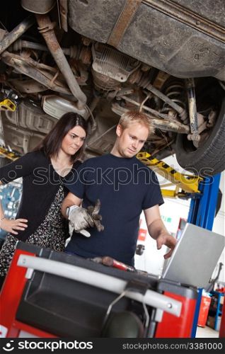Concentrated man and woman looking at laptop while standing in garage