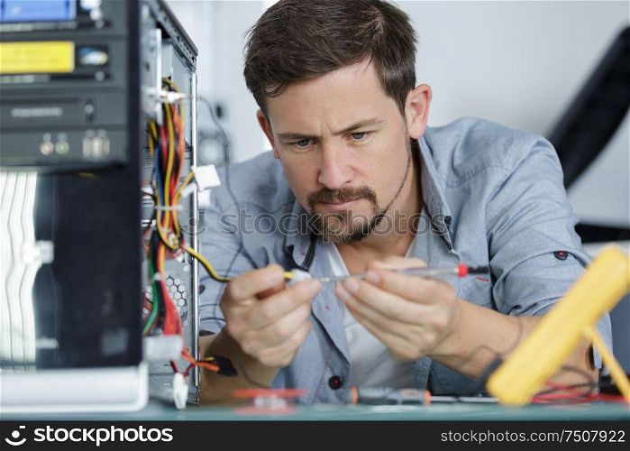 concentrated man connecting a cable onto a circuit board
