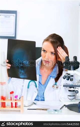 Concentrated medical doctor woman sitting at office table and analyzing patients roentgen&#xA;