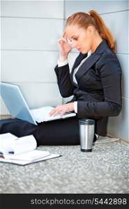 Concentrated modern business woman sitting on floor at office building and using laptop&#xA;