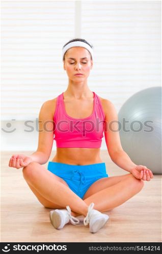 Concentrated pretty girl doing yoga exercises on floor&#xA;