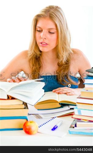 Concentrated teengirl sitting at table and searching in books&#xA;