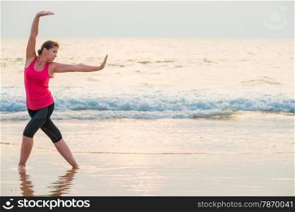 Concentrated woman doing yoga on the beach