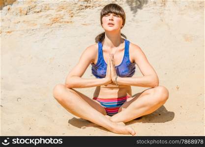concentrated woman doing yoga on the beach during the day