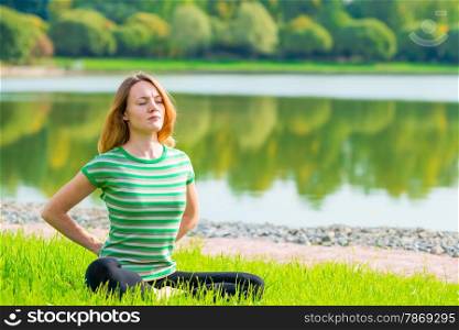 Concentrated woman doing yoga on the grass