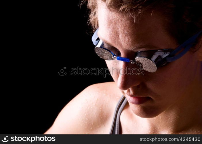 concentrated woman swimmer is looking downstairs on black background