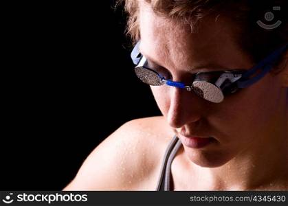 concentrated woman swimmer is looking downstairs on black background