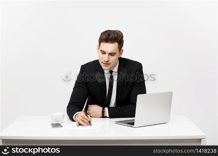 Concentrated young businessman writing documents at office desk. Concentrated young businessman writing documents at office desk.