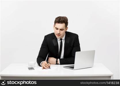 Concentrated young businessman writing documents at office desk. Concentrated young businessman writing documents at office desk.