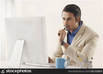 Concentrated young Indian businessman working on computer at office desk