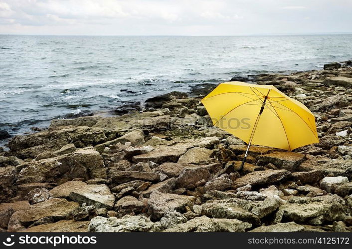 concept,cold sea and gray stones focus point on yellow umbrella