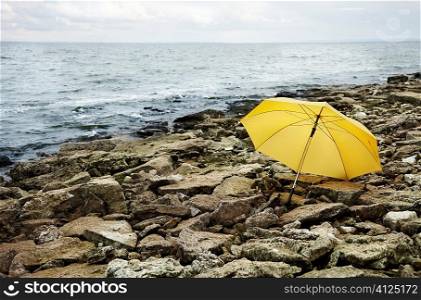 concept,cold sea and gray stones focus point on yellow umbrella