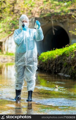 concept ecological disaster, environmental scientist with an infected sample of water from the sewer and walkie-talkie