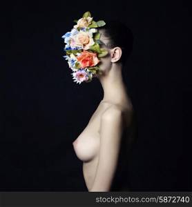 Concept fashion studio portrait of nude elegant lady with flower on her face