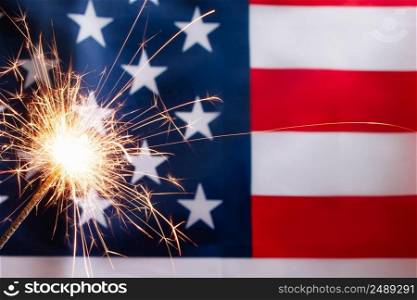 Concept for celebrating US Independence or Memorial Day. Sparkler on a background of the American flag.. Concept for celebrating US Independence or Memorial Day. Sparkler on a background of American flag.