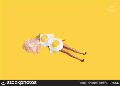 Concept for sunbathe. . Concept for sunbathe. Doll with fried eggs on yellow background