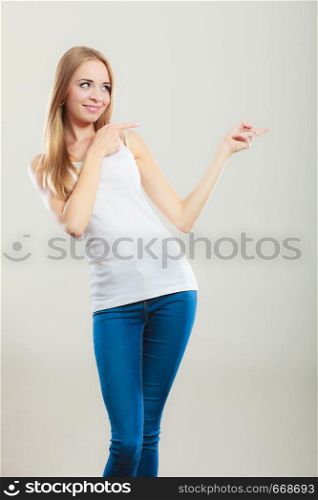 Concept girl advertisement product. Young woman casual style point finger showing something to side empty copy space.