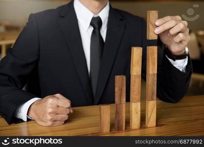 Concept growing value. hand of businessman pick up a wood block like bar graph growth