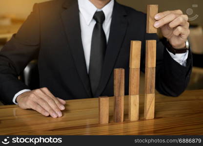 Concept growing value. hand of businessman pick up a wood block like bar graph growth