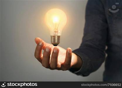 concept idea and inspiration saving power energy. man hand holding light bulb in room