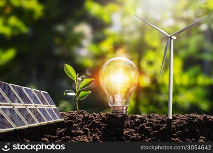 concept idea clean energy in nature. lightbulb with solar panel and wind turbine on soil