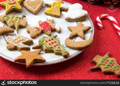 Concept image of Christmas fun with children - a variety of homemade gingerbreads on a red tablecloth in close-up.