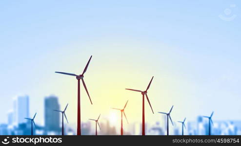 Concept of alternative electricity power with windmills on sunset background. Alternative wind energy