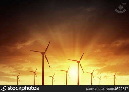 Concept of alternative electricity power with windmills on sunset background. Alternative wind energy