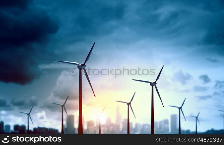 Concept of alternative electricity power with windmills on sunset background. Alternative wind energy