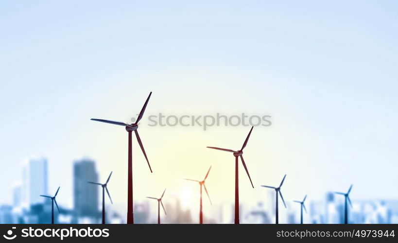 Concept of alternative electricity power with windmills on sunset background. Alternative wind energy