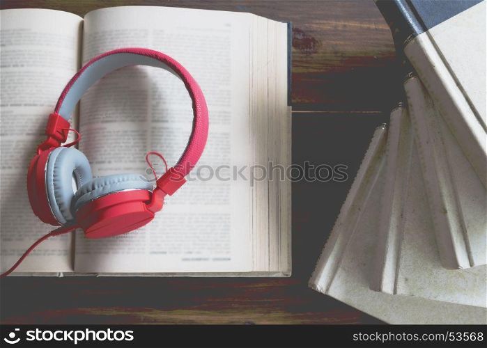 Concept of audiobook. Books on the table with headphones put on them.