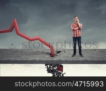 Concept of business collapse. Young man and red decreasing arrow breaking through floor