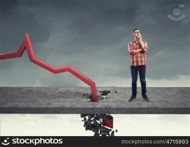 Concept of business collapse. Young man and red decreasing arrow breaking through floor