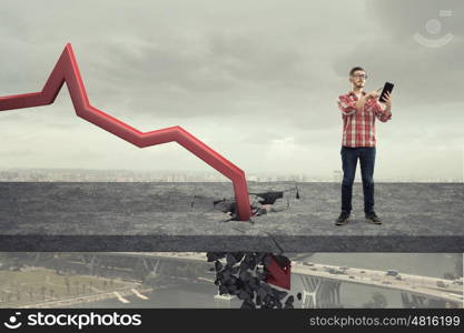 Concept of business collapse. Young man and red decreasing arrow breaking through floor