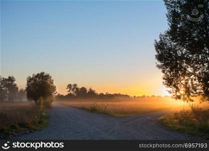 Concept of choice the correct way. Concept of choice the correct way. Beautiful landscape with sunrise over crossroads spliting in two ways. Rural crossroads on sunset background