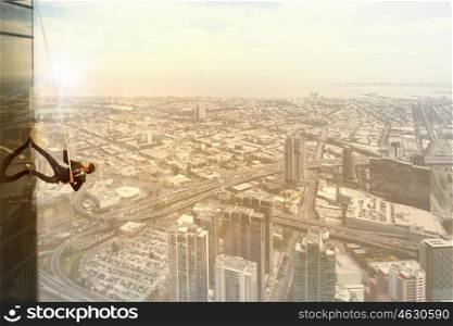 Concept of competition with businessman climbing office building with rope. Reach the top