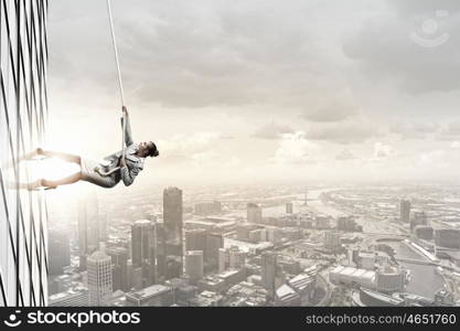 Concept of competition with businesswoman climbing office building with rope. Reach the top