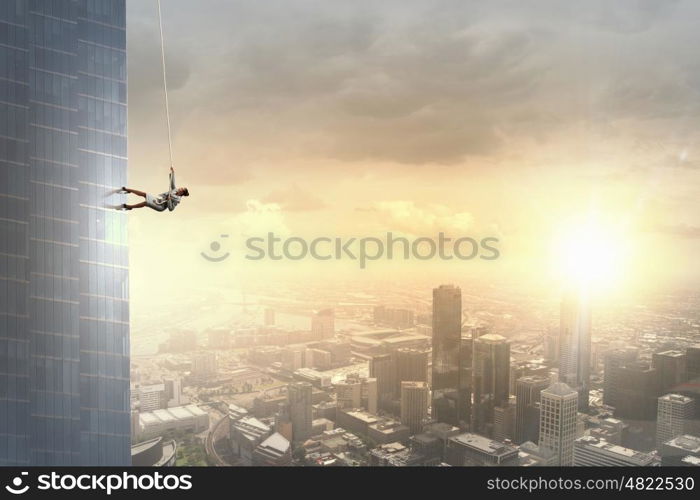 Concept of competition with businesswoman climbing office building with rope. Reach the top