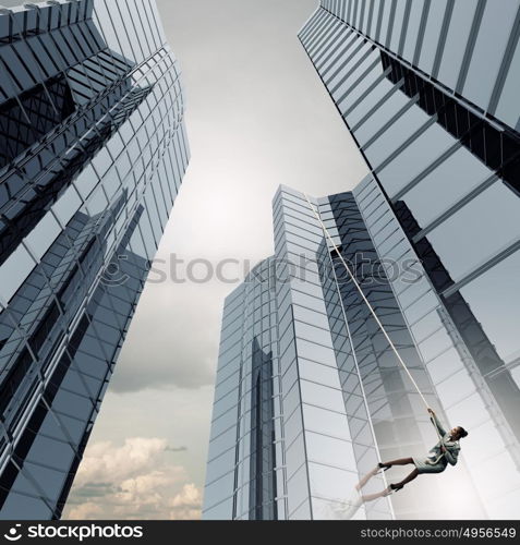 Concept of competition with businesswoman climbing office building with rope. Reach the top