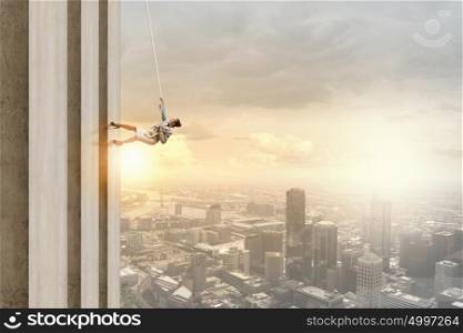 Concept of competition with businesswoman climbing office building with rope. Reach the top